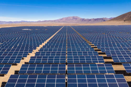 Aerial view of hundreds solar energy modules or panels rows along the dry lands at Atacama Desert, Chile. Huge Photovoltaic PV Plant in the middle of the desert from an aerial drone point of view