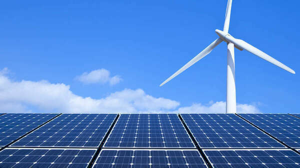 Solar panels and wind turbine against blue sky
