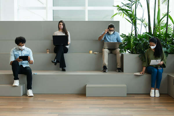 Serious group of entrepreneurs with face mask working and typing in laptop in co-working open space. 